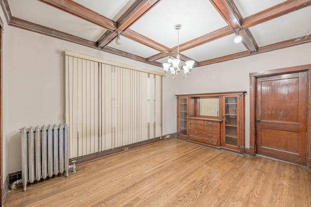 unfurnished room featuring radiator, coffered ceiling, light hardwood / wood-style flooring, beam ceiling, and a chandelier