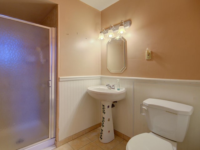 bathroom with tile patterned flooring, toilet, and a shower with door