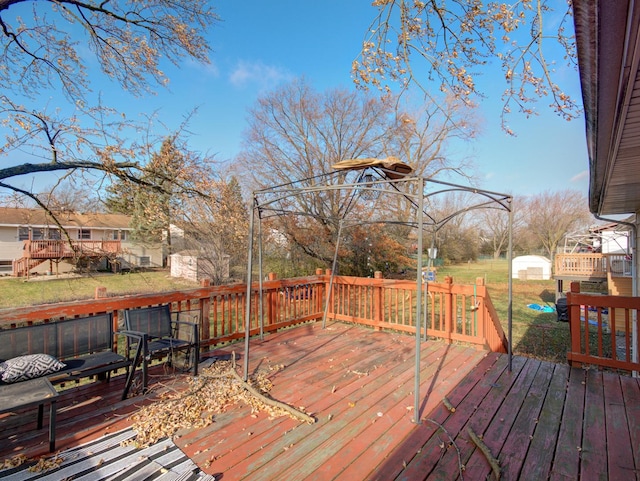 wooden deck featuring a yard and a storage shed