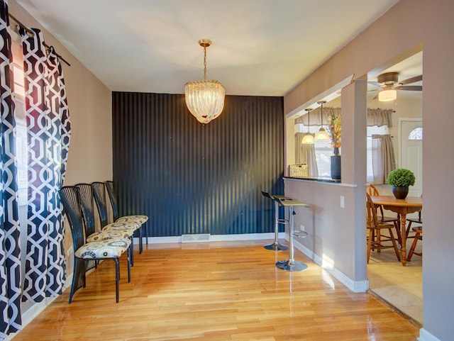 interior space featuring hanging light fixtures, wood-type flooring, and ceiling fan with notable chandelier