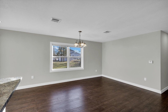 unfurnished dining area featuring dark hardwood / wood-style flooring, a textured ceiling, and a chandelier