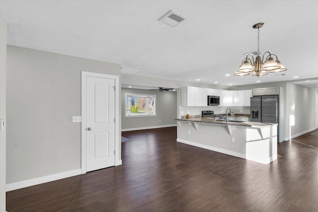 kitchen with appliances with stainless steel finishes, ceiling fan with notable chandelier, dark wood-type flooring, sink, and hanging light fixtures