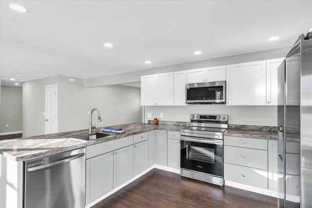 kitchen featuring white cabinetry, sink, dark hardwood / wood-style flooring, kitchen peninsula, and appliances with stainless steel finishes