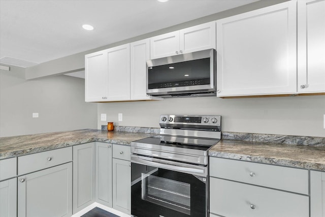 kitchen with stone counters, white cabinets, and stainless steel appliances