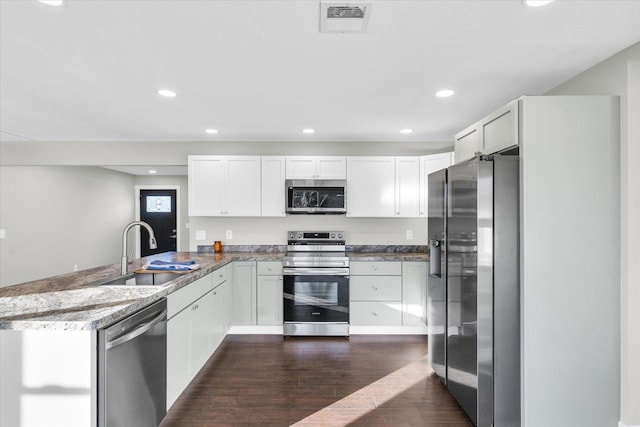 kitchen with sink, dark hardwood / wood-style floors, kitchen peninsula, white cabinets, and appliances with stainless steel finishes