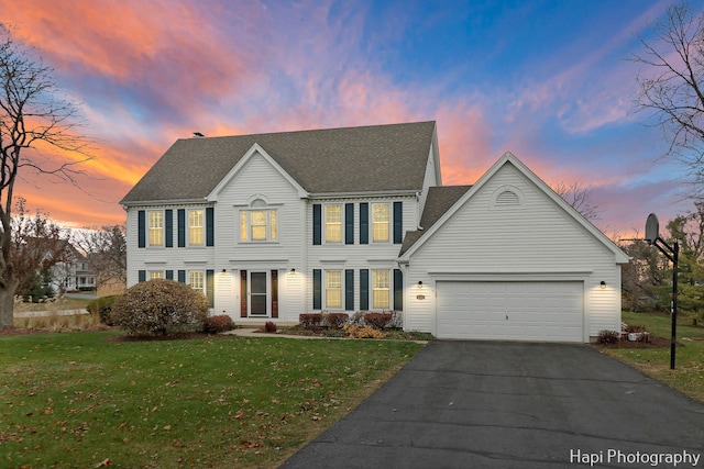 colonial home with a lawn and a garage