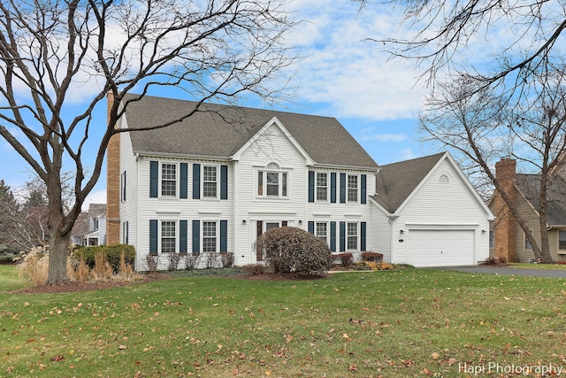 colonial home with a garage and a front lawn