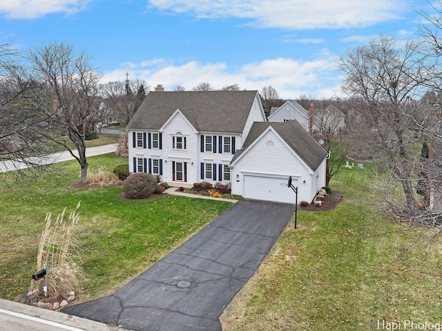 colonial inspired home with a garage and a front lawn