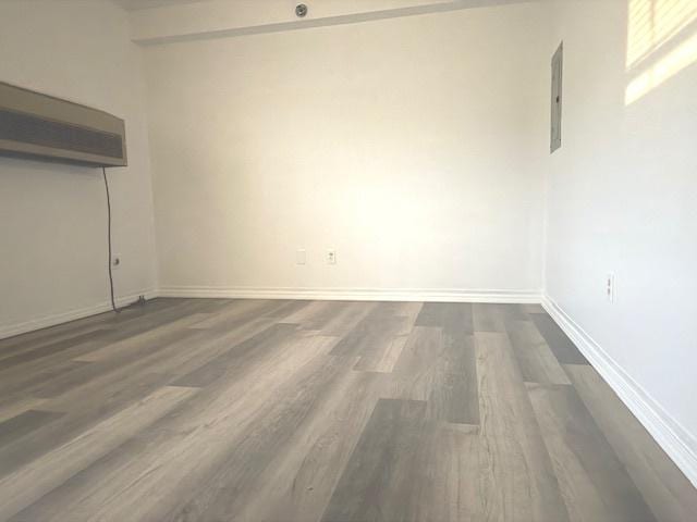 unfurnished room with electric panel and dark wood-type flooring