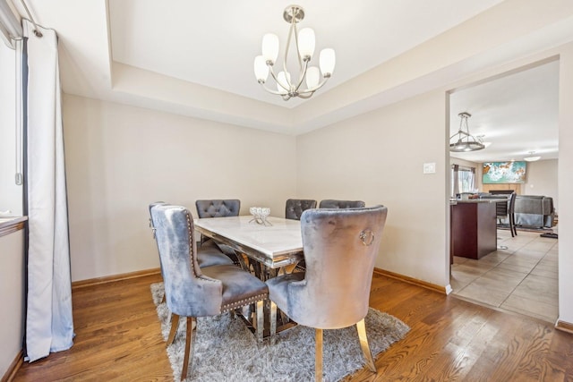 dining room featuring hardwood / wood-style flooring, a notable chandelier, and a raised ceiling