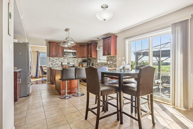 kitchen featuring decorative backsplash, appliances with stainless steel finishes, light stone countertops, light tile patterned floors, and pendant lighting