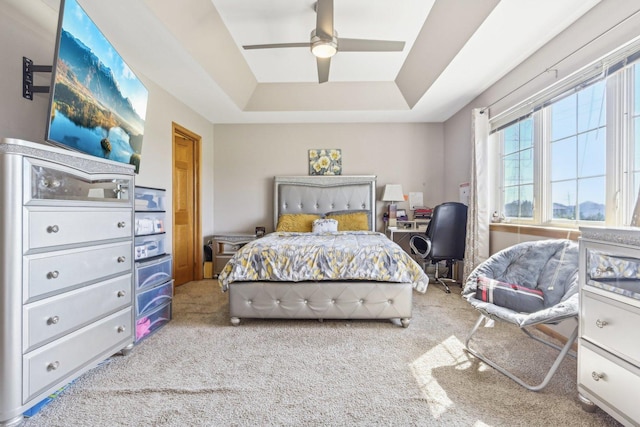 carpeted bedroom featuring a raised ceiling and ceiling fan