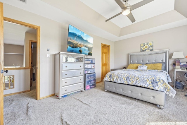 carpeted bedroom with a tray ceiling and ceiling fan