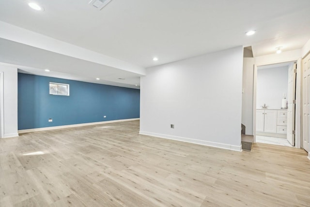 basement featuring light wood-type flooring and sink