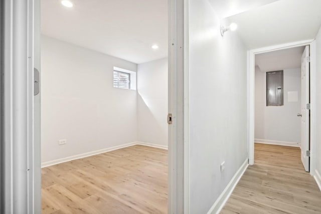 hallway featuring electric panel and light hardwood / wood-style flooring