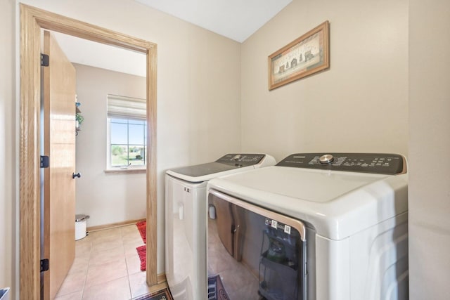 laundry area with independent washer and dryer and light tile patterned floors