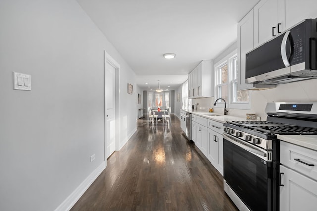 kitchen featuring white cabinetry, sink, stainless steel appliances, dark hardwood / wood-style floors, and pendant lighting