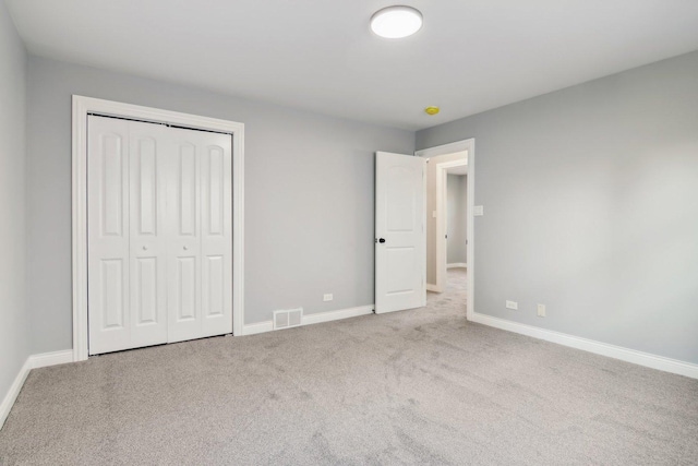 unfurnished bedroom with light colored carpet and a closet