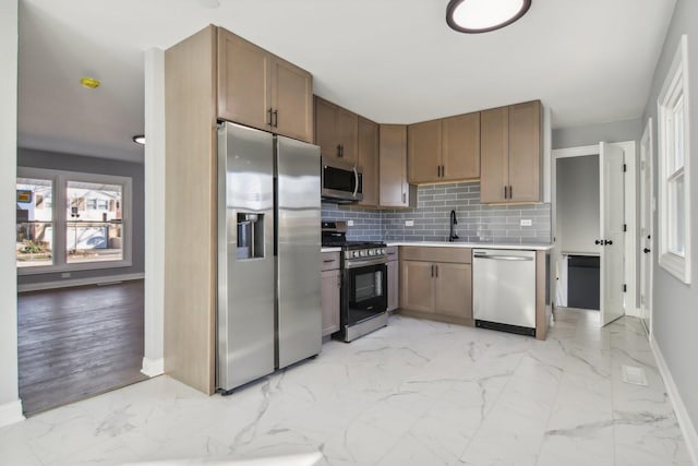 kitchen featuring tasteful backsplash, sink, light wood-type flooring, and appliances with stainless steel finishes