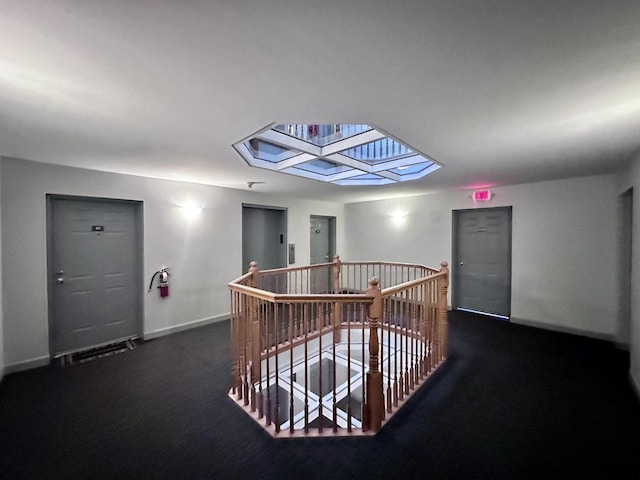 hall with dark colored carpet and a skylight