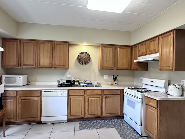 kitchen with light tile patterned floors, white appliances, and sink