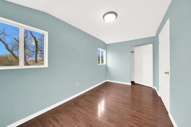 spare room with dark hardwood / wood-style flooring and lofted ceiling