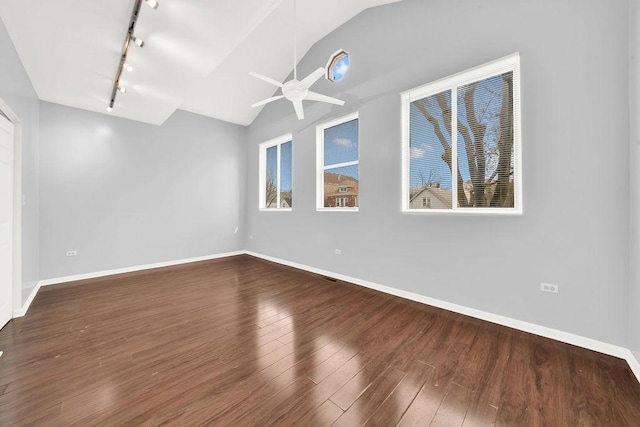 unfurnished room with a healthy amount of sunlight, track lighting, wood-type flooring, and vaulted ceiling