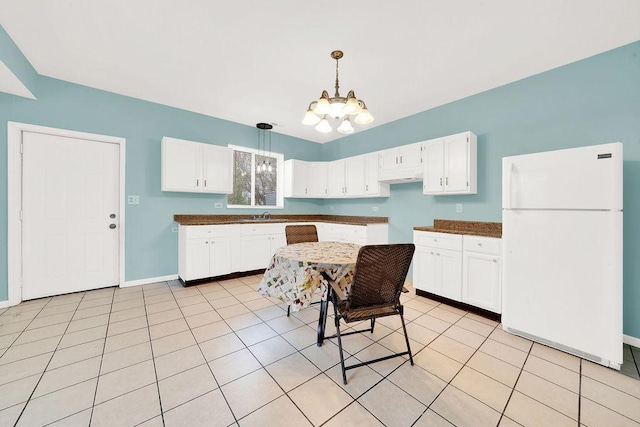 kitchen with light tile patterned floors, white fridge, pendant lighting, a chandelier, and white cabinets