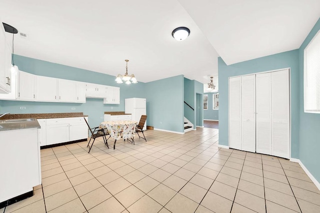 kitchen with pendant lighting, white cabinets, light tile patterned floors, white fridge, and a chandelier