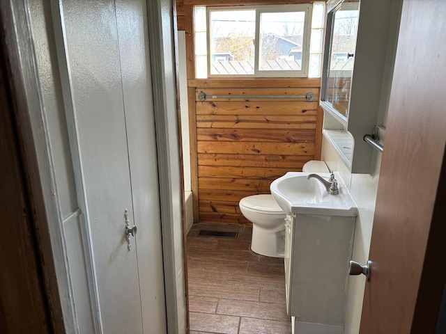 bathroom featuring vanity, wood walls, toilet, and wood-type flooring