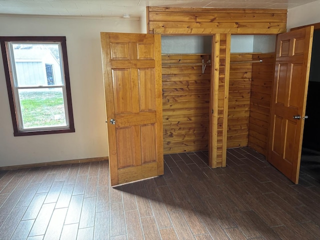 unfurnished bedroom with wooden walls and dark hardwood / wood-style floors