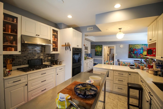 kitchen featuring kitchen peninsula, appliances with stainless steel finishes, backsplash, white cabinets, and hanging light fixtures