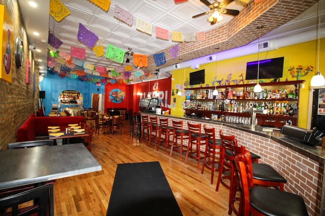 bar featuring hardwood / wood-style flooring and ceiling fan