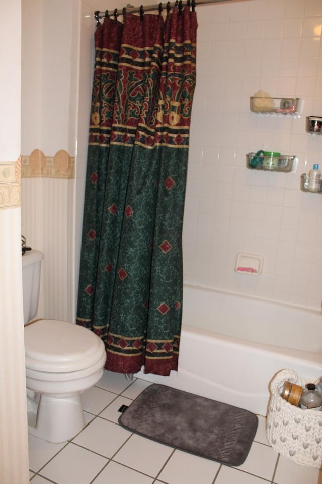 bathroom featuring tile patterned flooring, toilet, and shower / tub combo with curtain