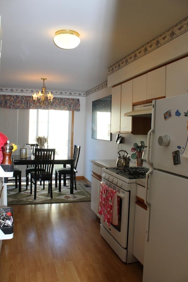 kitchen with pendant lighting, white appliances, cream cabinets, light hardwood / wood-style flooring, and a notable chandelier