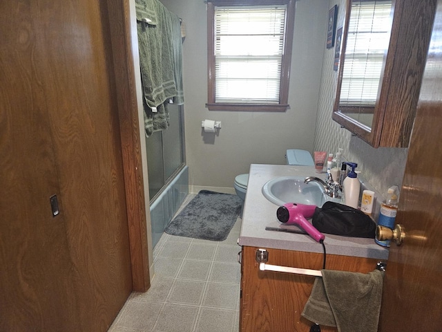 full bathroom featuring vanity, toilet, and shower / bath combination with glass door