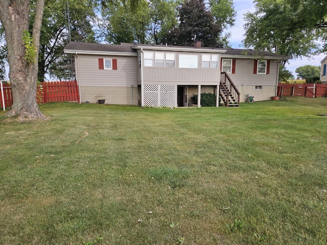 back of house featuring a lawn and a sunroom