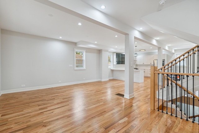 basement with stainless steel fridge and light hardwood / wood-style flooring