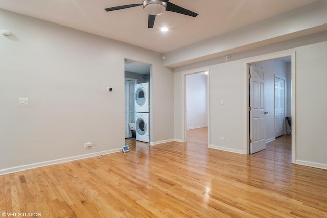 unfurnished room with light wood-type flooring, ceiling fan, and stacked washer / drying machine