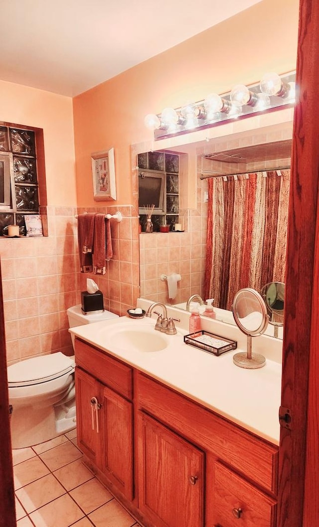 bathroom featuring tile patterned floors, vanity, tile walls, and toilet