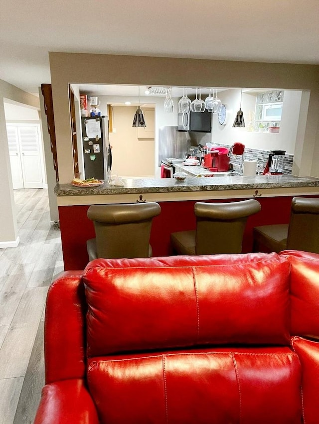 bar featuring stainless steel refrigerator, hardwood / wood-style floors, and pendant lighting