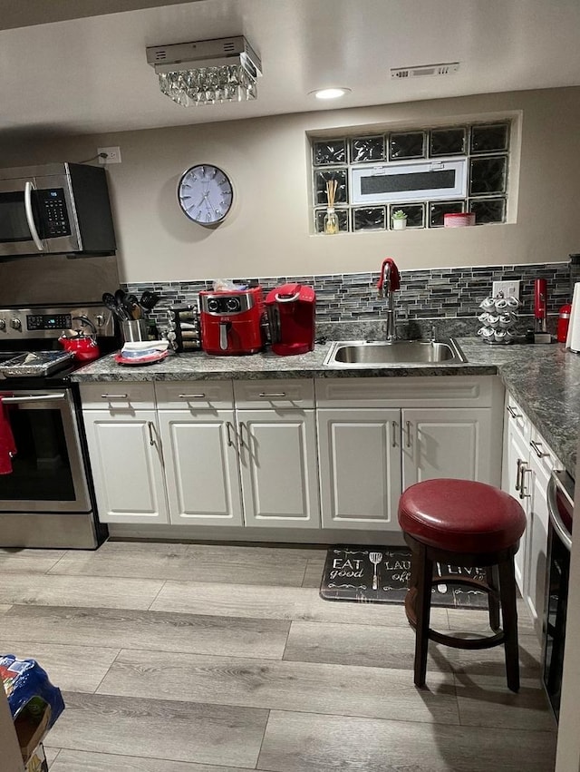 kitchen featuring white cabinetry, sink, stainless steel appliances, and light hardwood / wood-style flooring