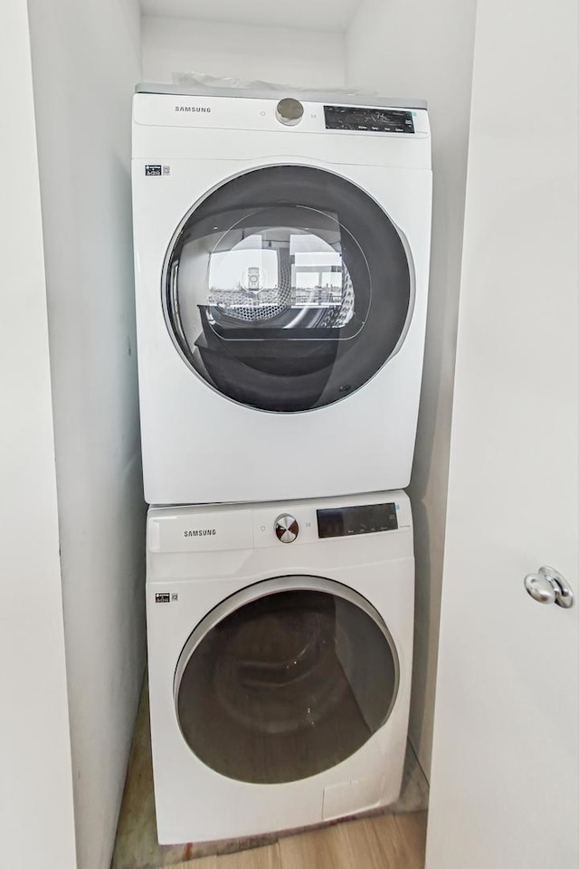 washroom with light hardwood / wood-style flooring and stacked washer / dryer