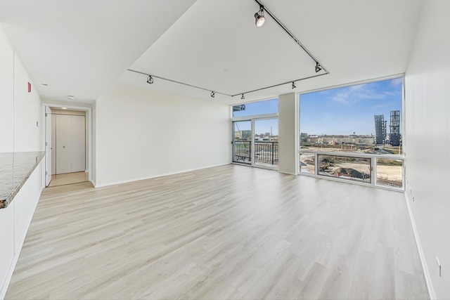 unfurnished living room with light wood-type flooring and rail lighting