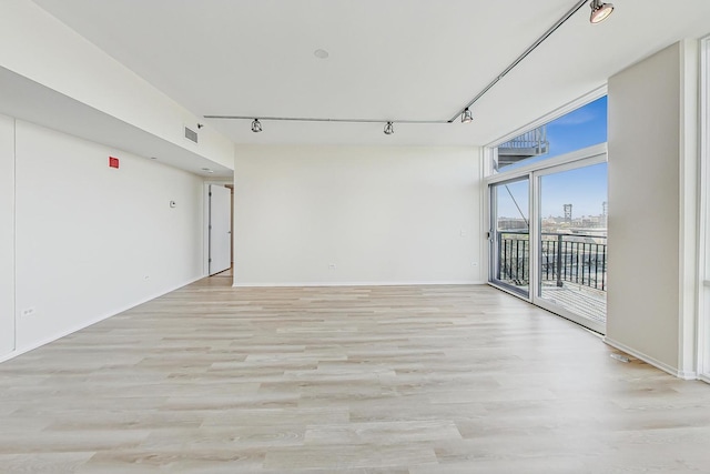 spare room featuring expansive windows, light hardwood / wood-style floors, and track lighting