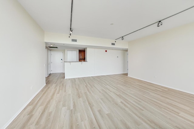 unfurnished living room with light wood-type flooring and track lighting