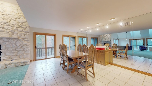 tiled dining space featuring a stone fireplace