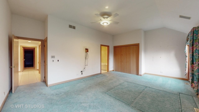 unfurnished bedroom featuring lofted ceiling, a closet, ceiling fan, and light colored carpet