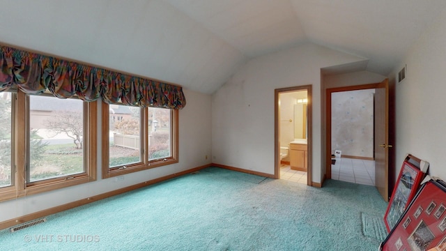 bedroom with connected bathroom, light colored carpet, and vaulted ceiling