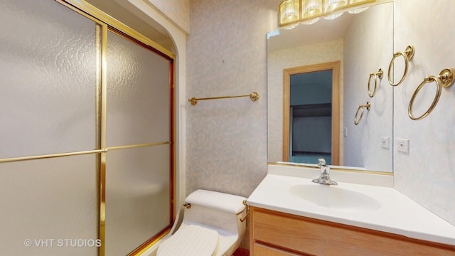 bathroom featuring a shower with door, vanity, and toilet